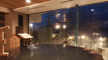 A hot spring bath with a wooden bench and a rope barrier.