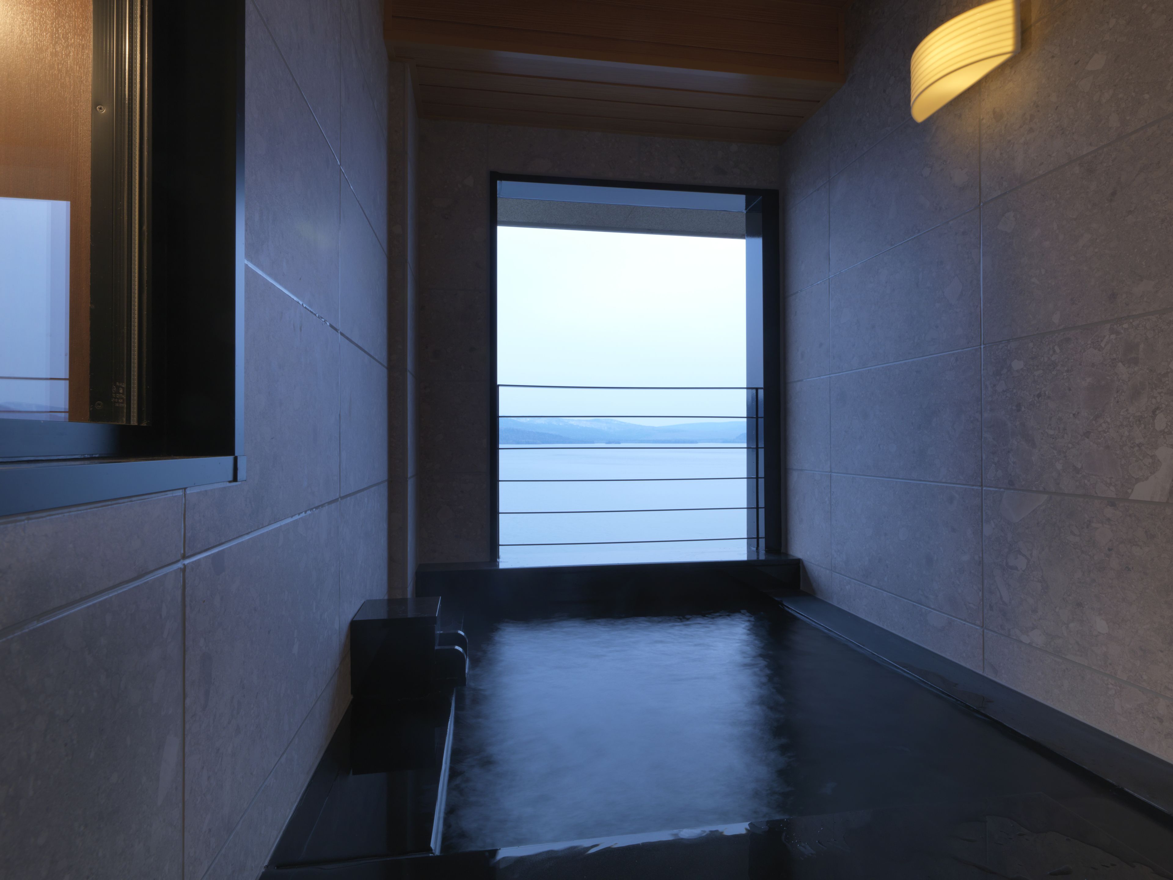 A corridor with a view of a body of water through a large window.