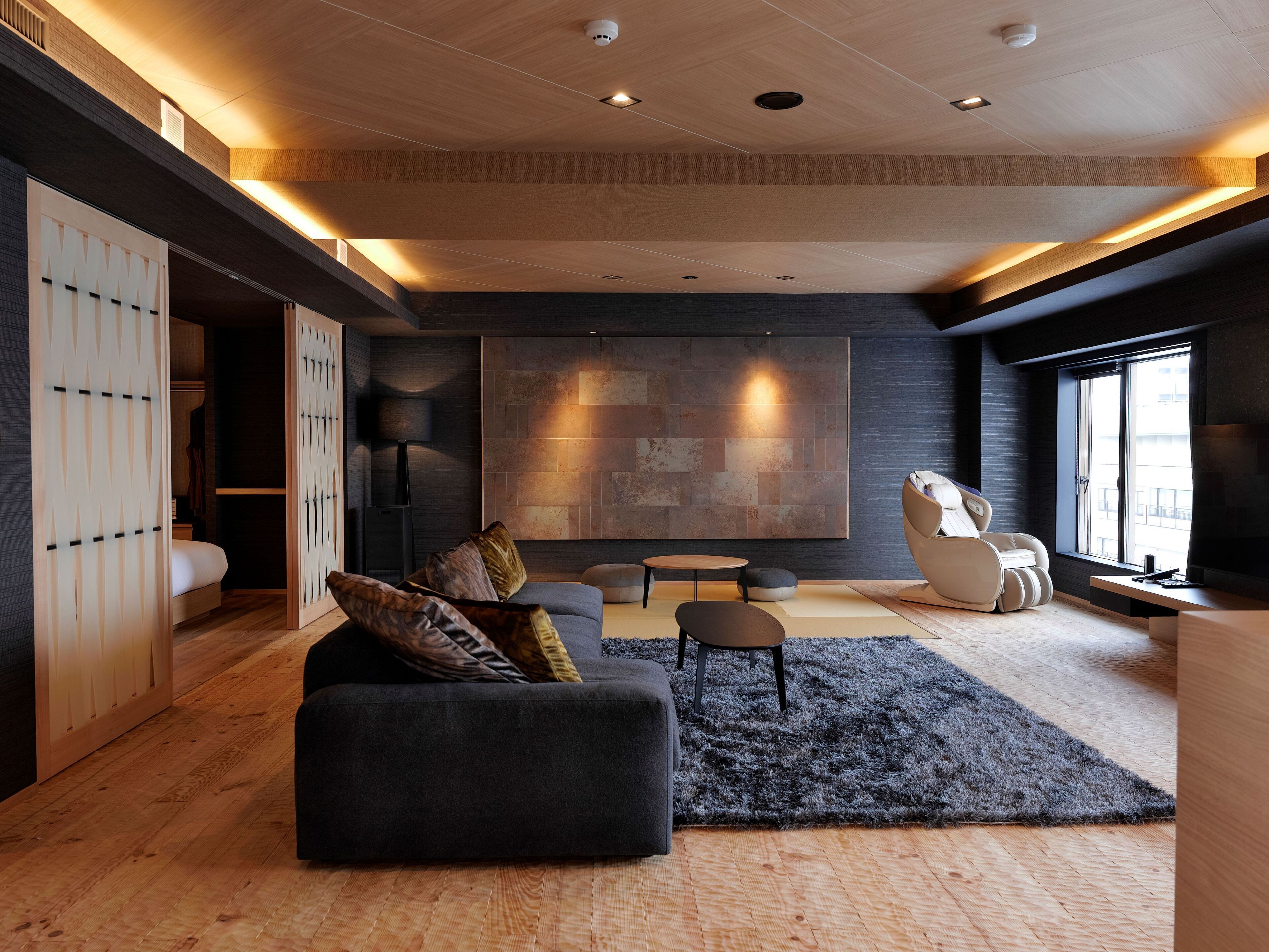 Una sala de estar moderna con un sofá oscuro, una silla blanca y una gran obra de arte abstracto en la pared.