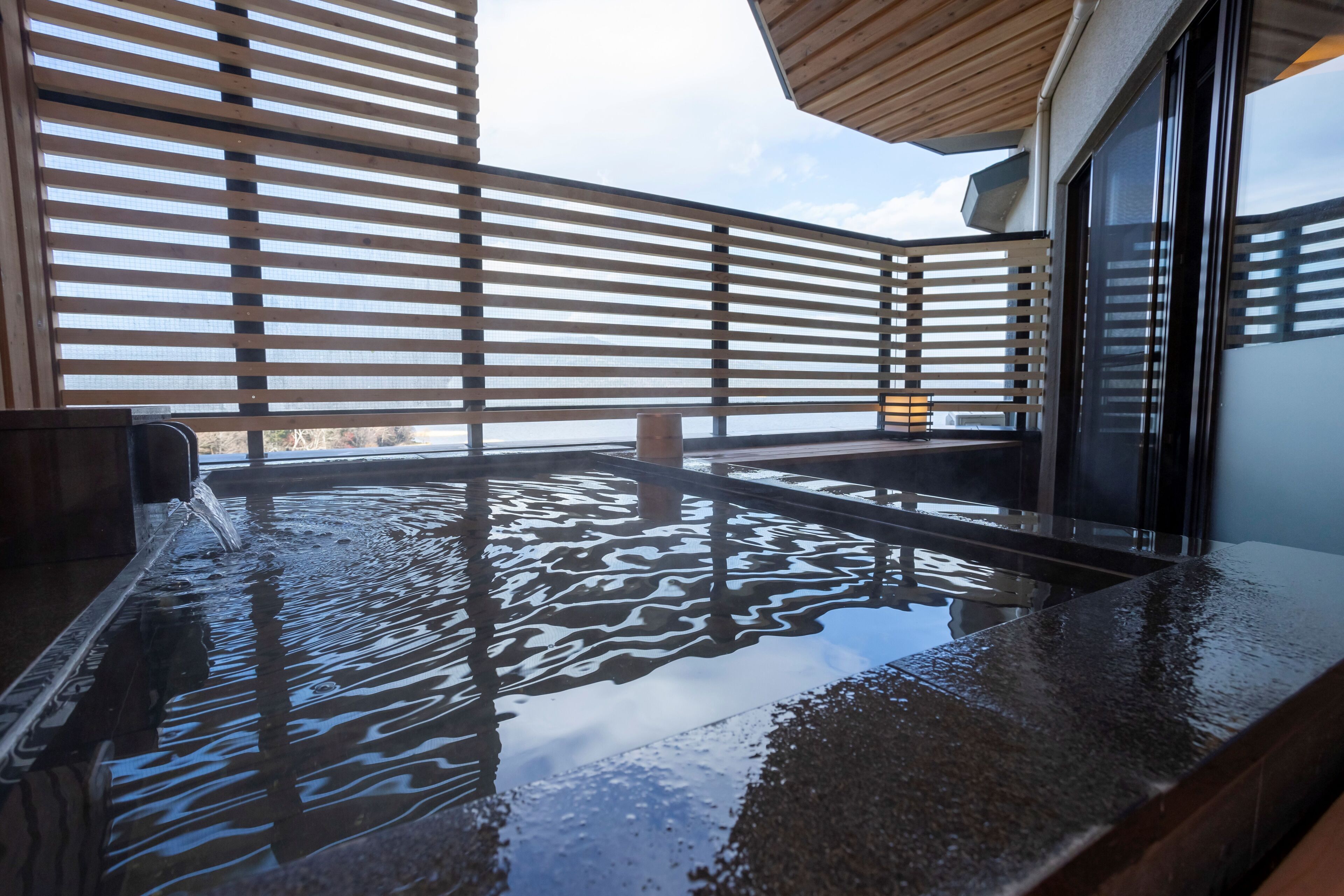 A hot tub with a wooden deck and a view of the sky.