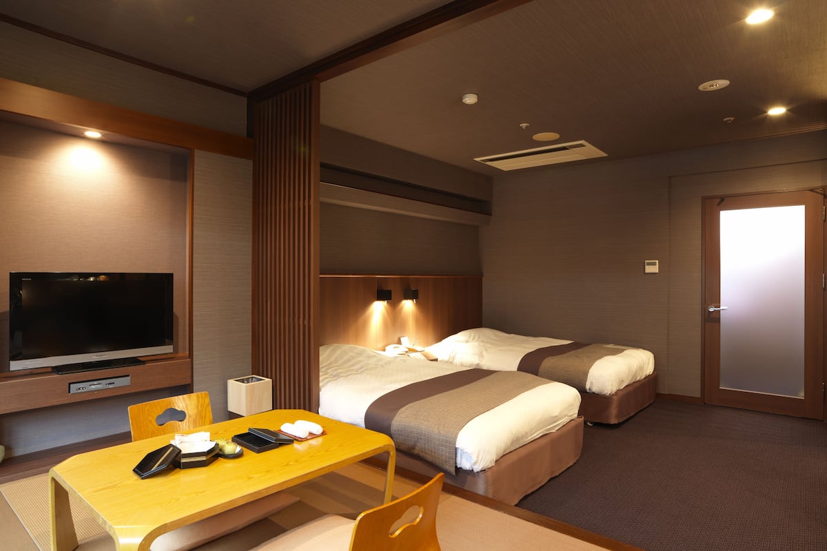 A hotel room with a bed, bedside tables, a TV, and a desk with a chair.