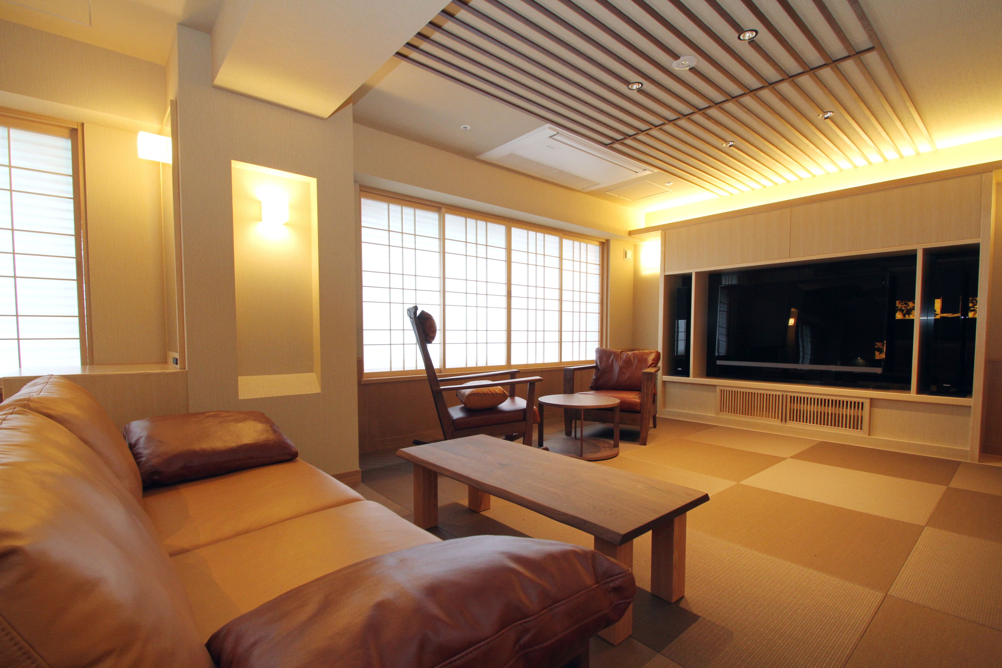 A modern living room with a leather sofa, a wooden coffee table, and a TV mounted on the wall.