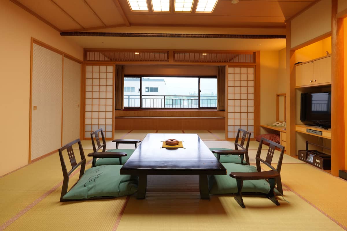 A traditional Japanese room with tatami flooring, a low table, and four chairs.