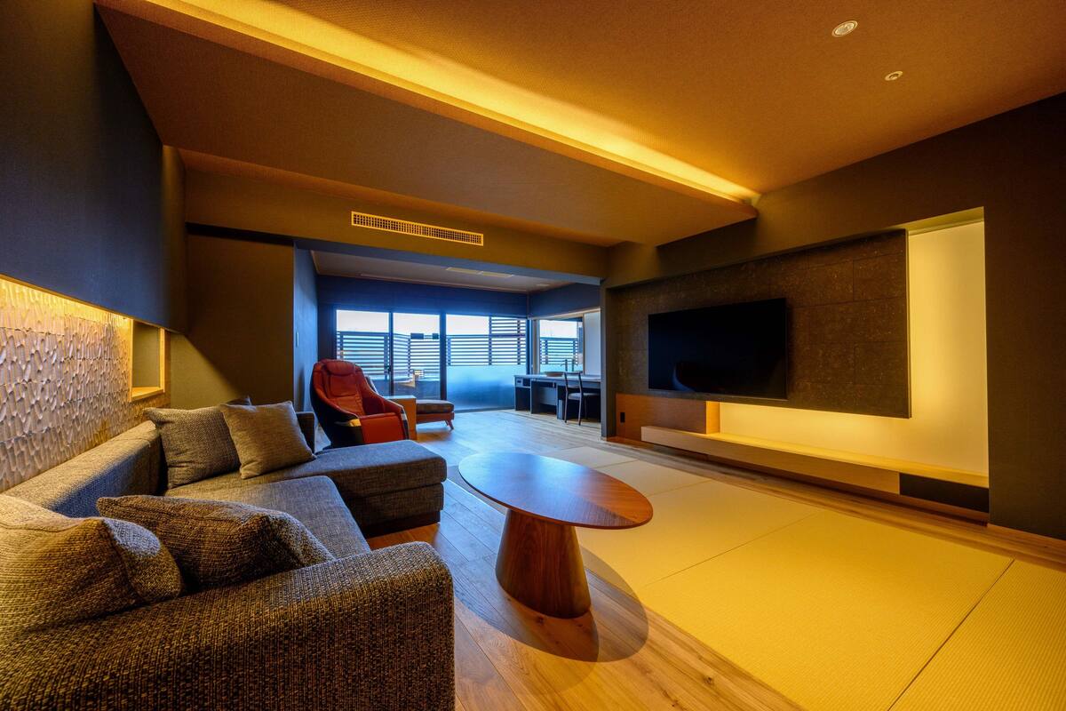 A modern living room with a sofa, a coffee table, and a flat-screen TV mounted on the wall.