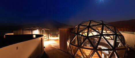 A geodesic dome structure on a rooftop with a starry night sky in the background.