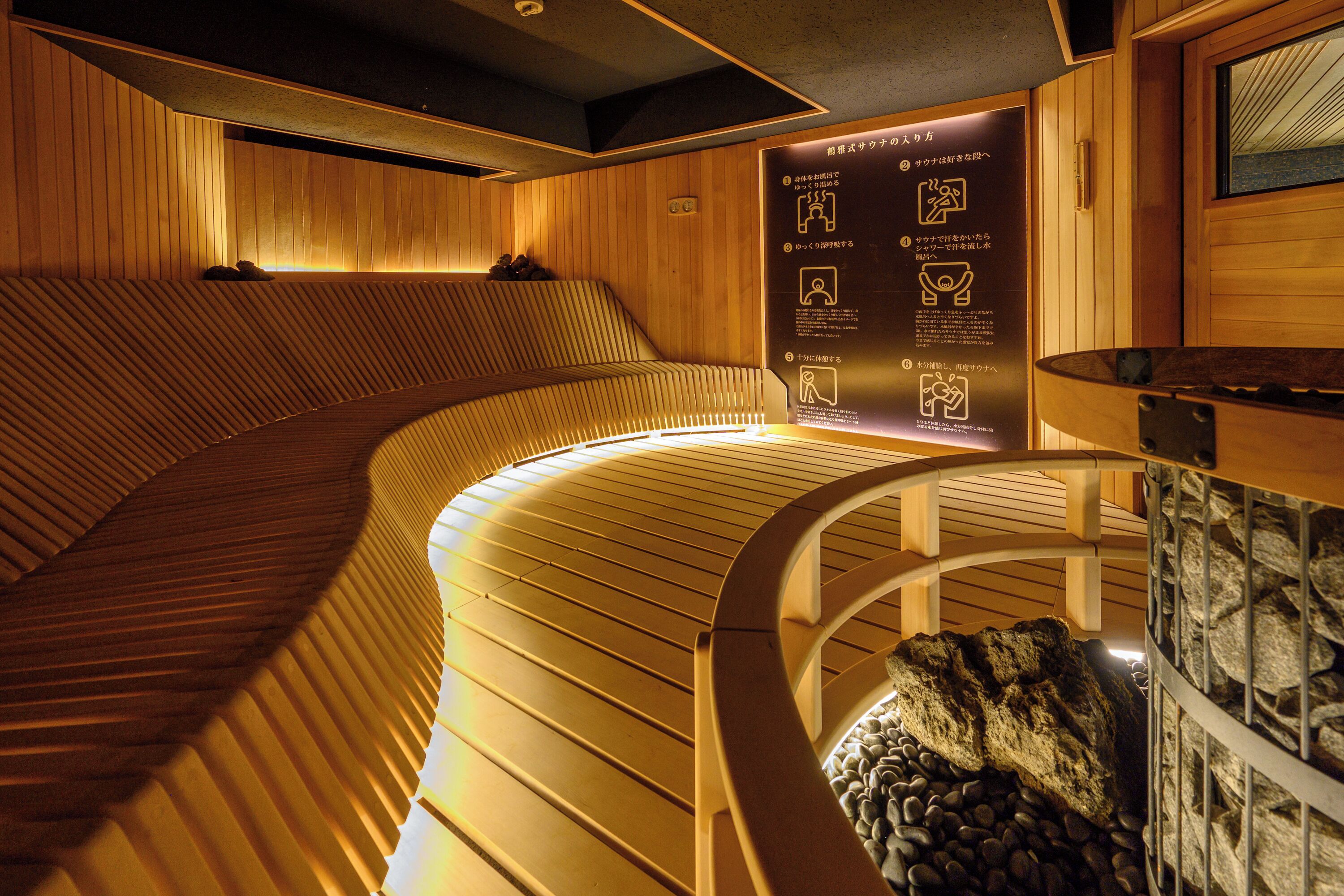 A wooden sauna with a curved bench, a stone wall, and a sign with instructions.