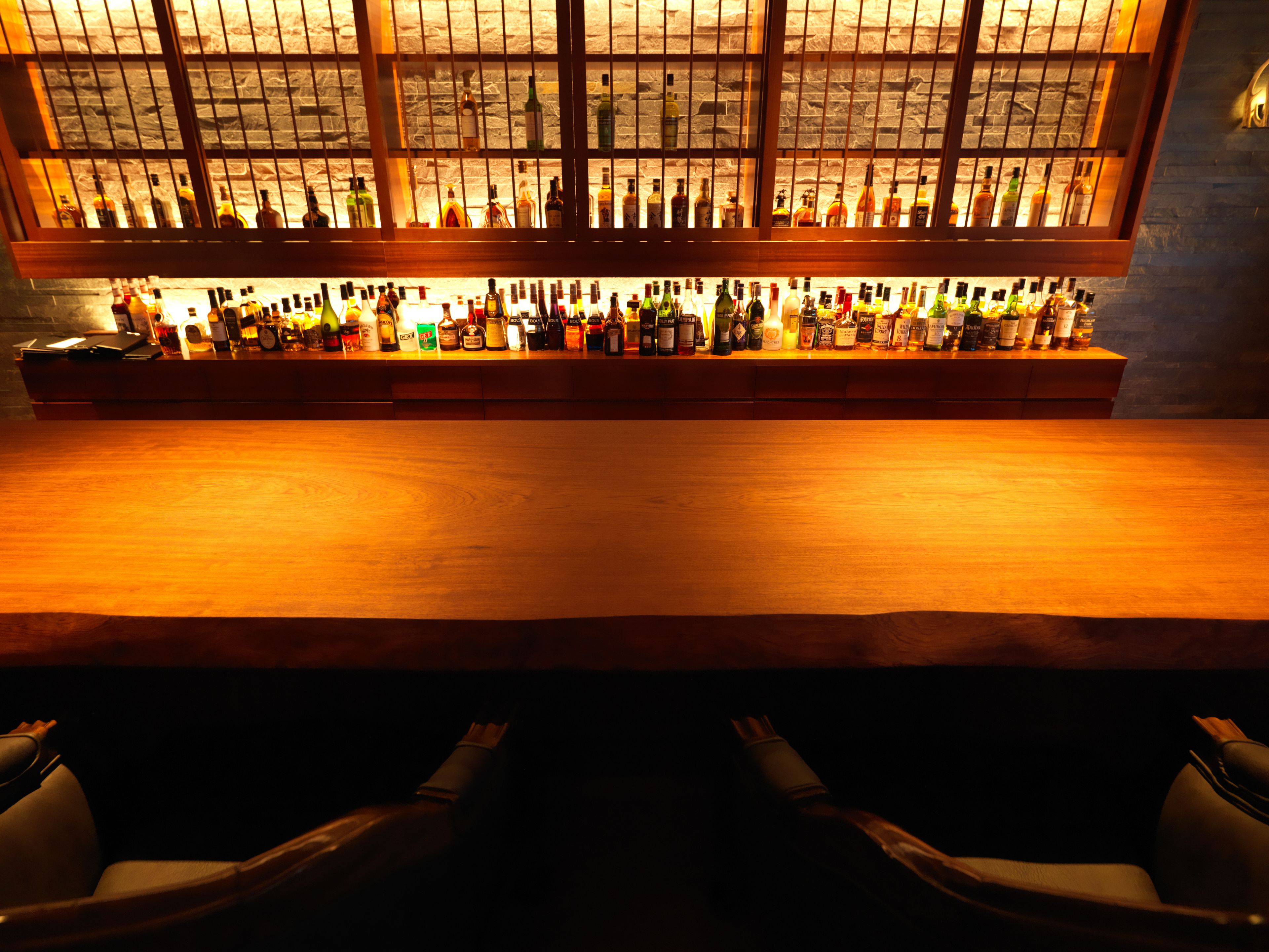 A bar with a long counter and a variety of bottles.
