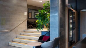 Una escalera moderna con barandilla, un espacio de descanso con una mesa redonda y una planta en maceta.