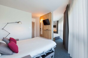 A modern hotel room with a bed, a desk, a lamp, and a TV. - Hotel Campanile Metz Nord - Talange (Talange)