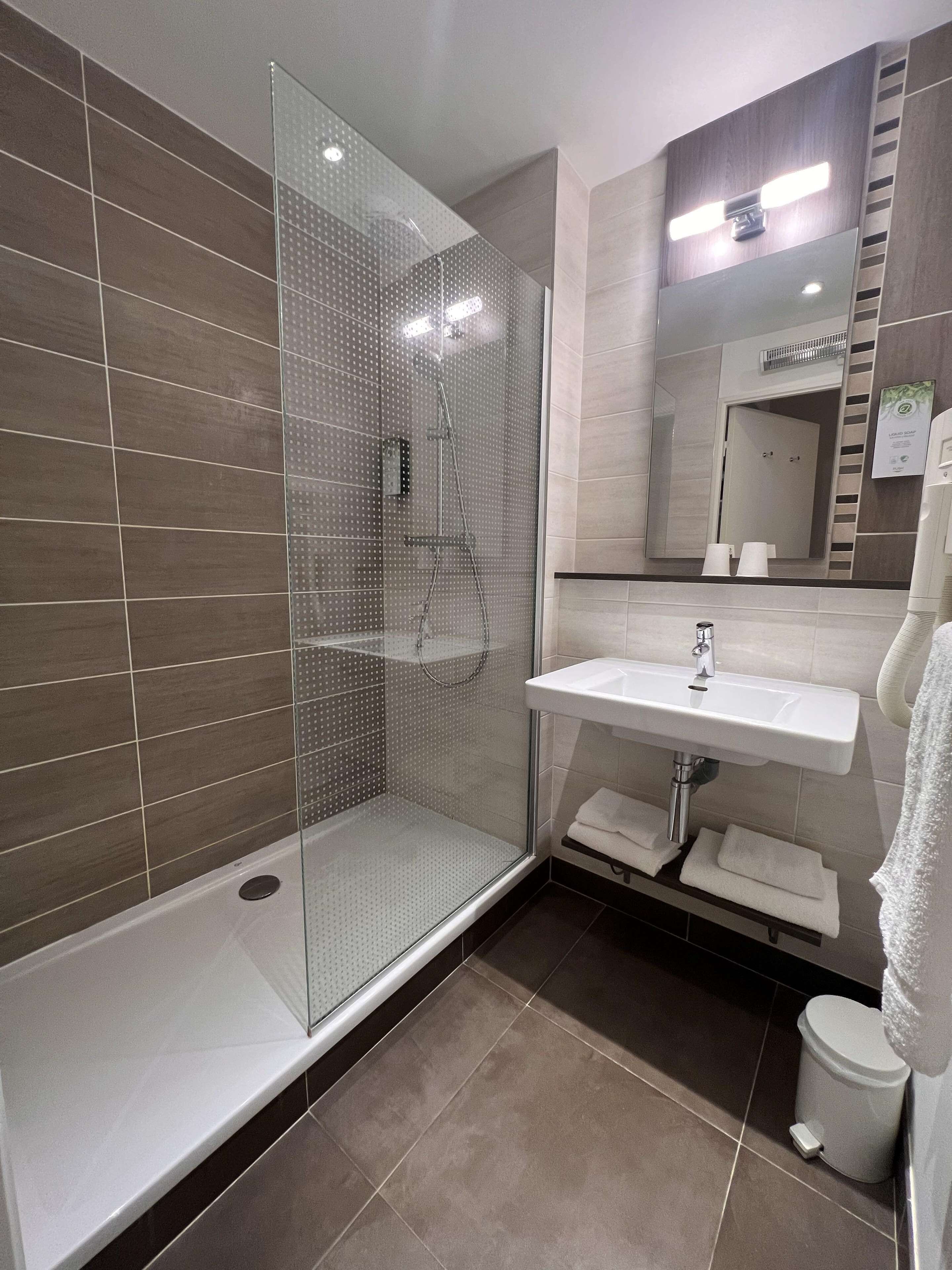 A modern bathroom with a glass-enclosed shower, a white sink, and a mirror above the sink.