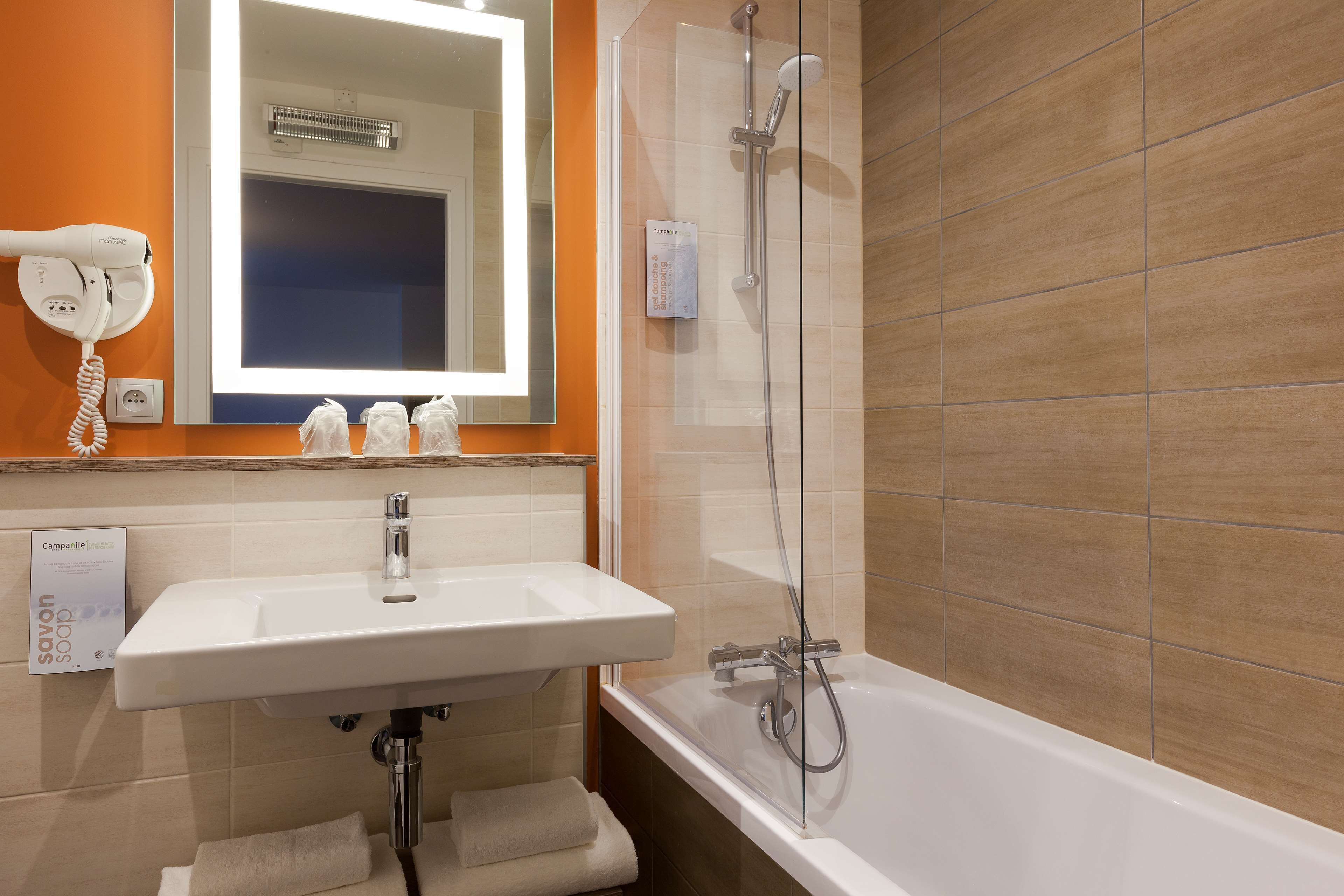 Un baño con lavamanos blanco, un espejo, secador de pelo y ducha.