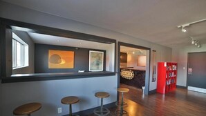 Een modern interieur met een bar, krukken, een boekenkast en kunstwerken aan de muren.