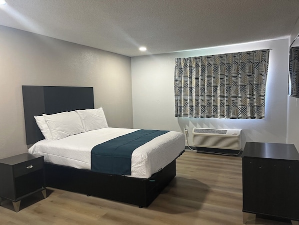 A modern bedroom with a bed, bedside tables, a heater, and patterned curtains. - Motel 6 - Las Vegas, NV – Downtown Fremont St Experience (Las Vegas)