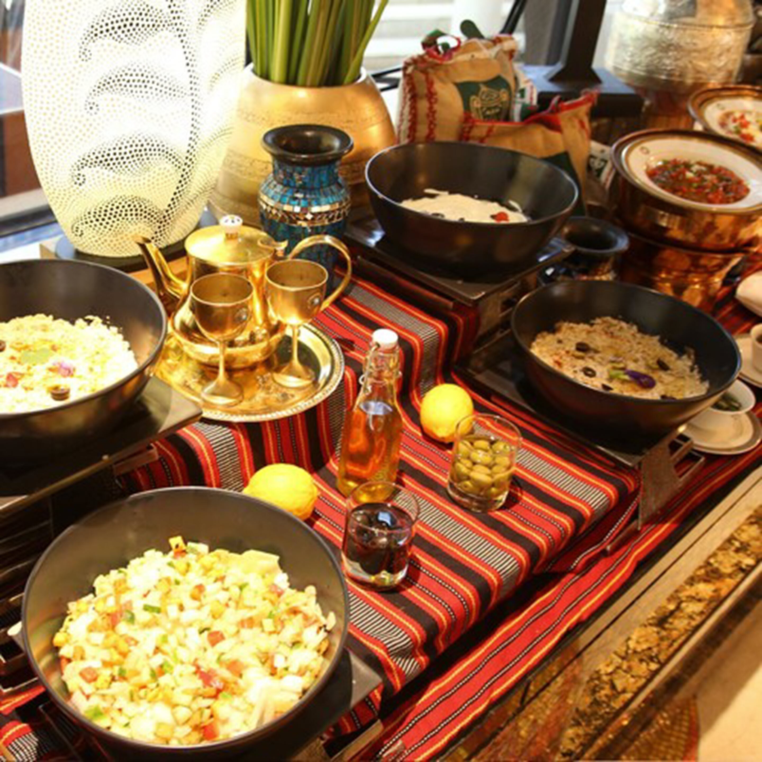A dining table with various dishes, a patterned tablecloth, and traditional serving ware.
