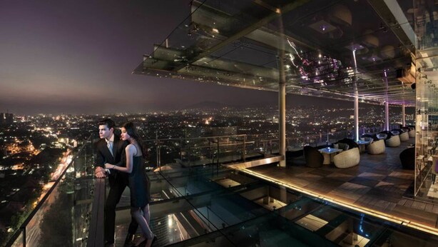 A high-rise hotel with a glass-enclosed terrace overlooking a cityscape at night. - The Trans Luxury Hotel (Bandung)