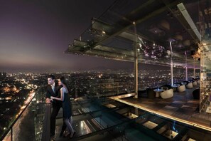 A high-rise hotel with a glass-enclosed terrace overlooking a cityscape at night. - The Trans Luxury Hotel (Bandung)