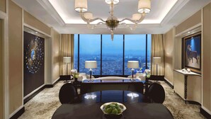 A spacious hotel conference room with a large table, chairs, a chandelier, and a city view through large windows. - The Trans Luxury Hotel (Bandung)
