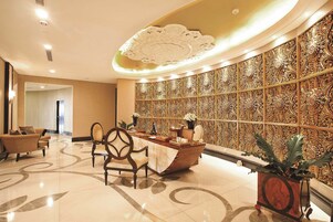 A lobby with a reception desk, seating area, and decorative wall panels.