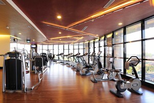 Un gimnasio con máquinas de cardio, máquinas de pesas y un amplio ventanal que proporciona luz natural.