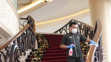 A person cleaning a staircase with a red carpet and ornate metal railings.