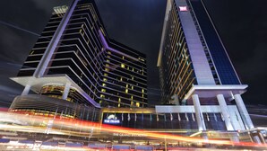 A modern hotel with a prominent glass facade, multiple floors, and a large entrance area. - The Trans Luxury Hotel (Bandung)