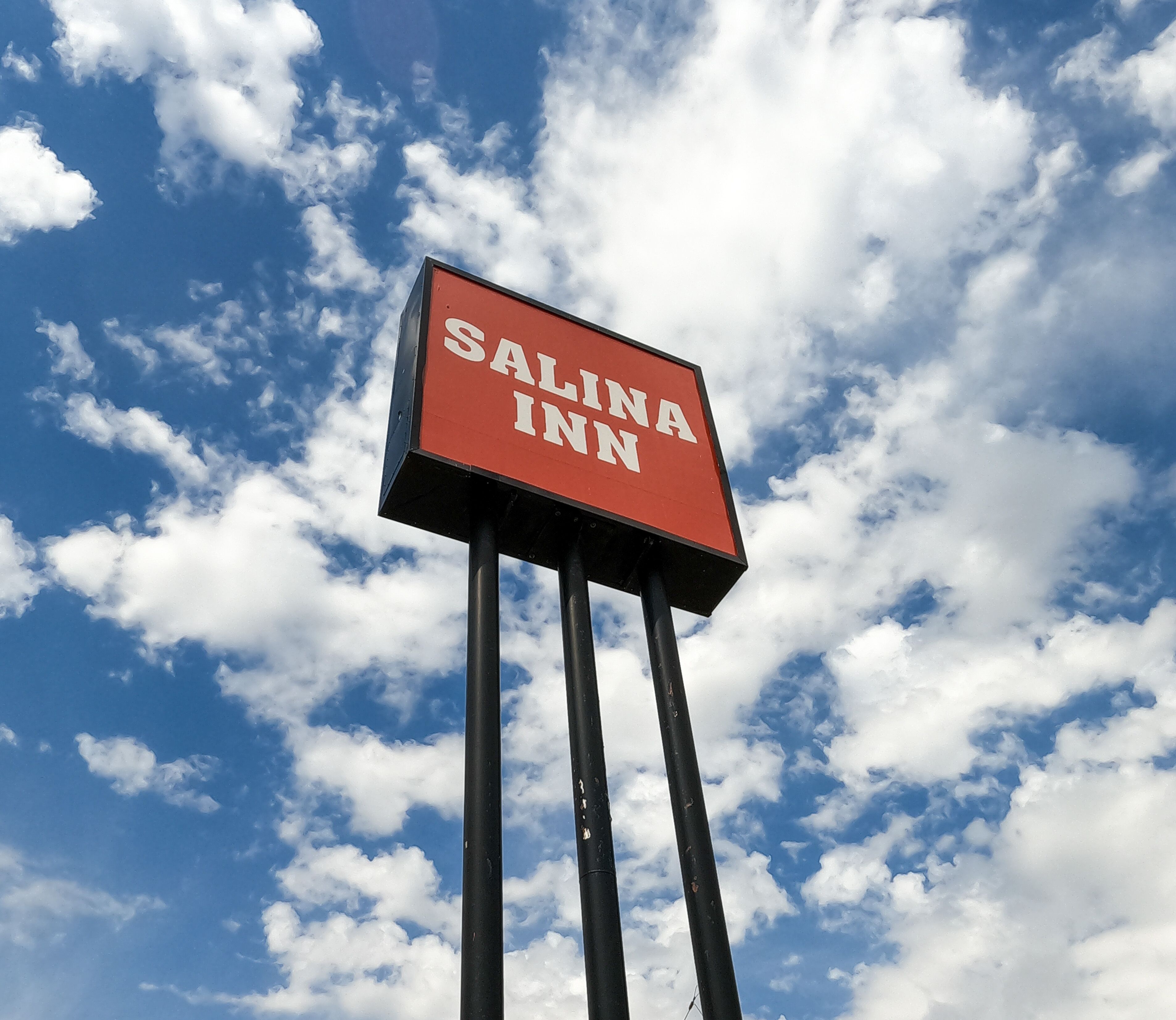 A sign for Salina Inn against a sky with clouds.