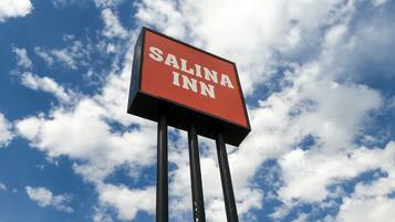 A sign for Salina Inn against a sky with clouds.