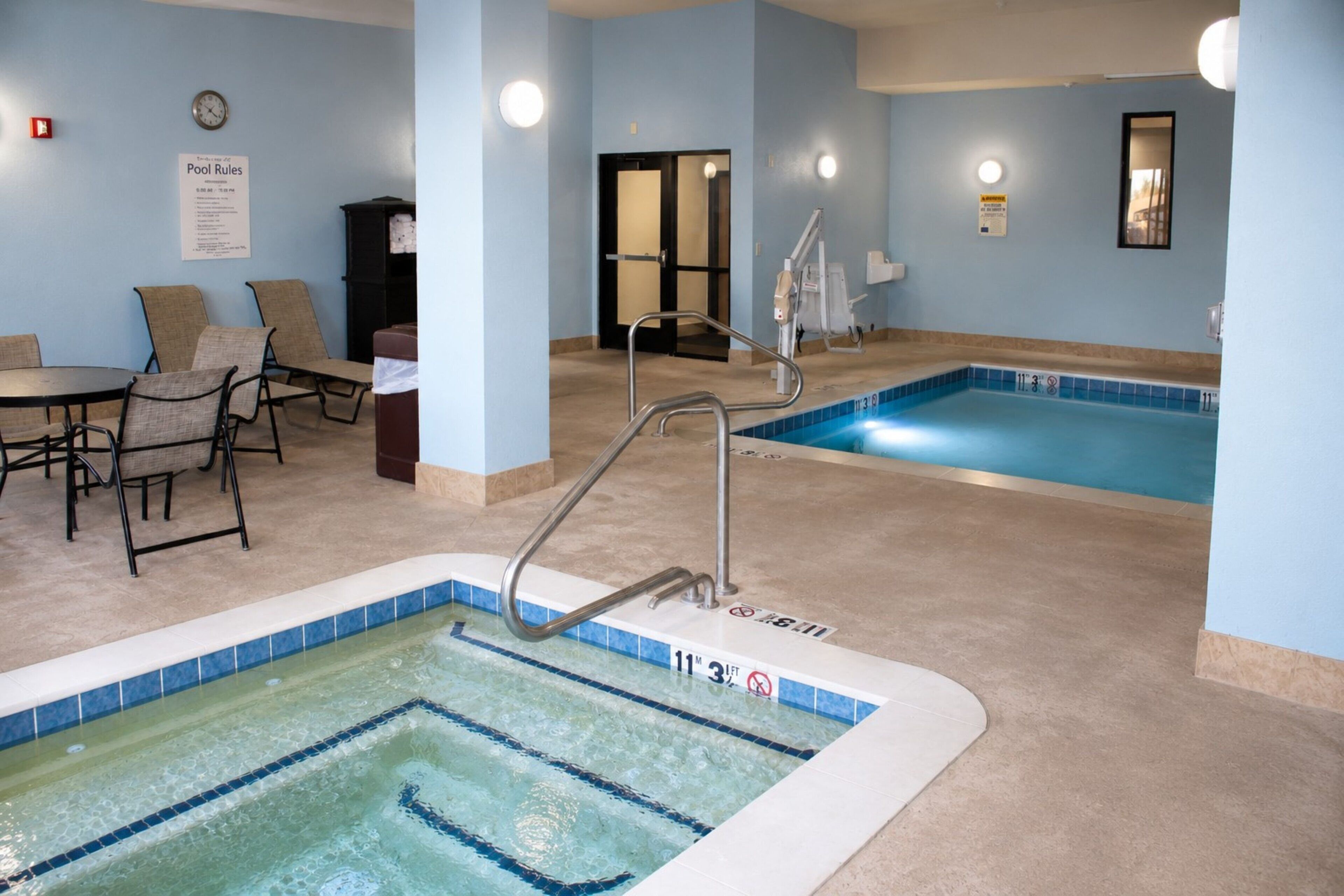 A pool area with a hot tub, lounge chairs, and a pool table.