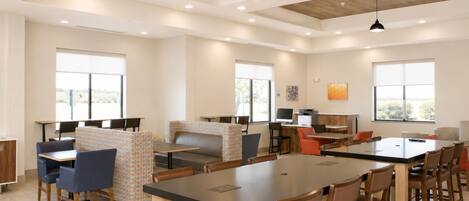 Un comedor moderno con mesas altas, cabinas y una mesa central grande.