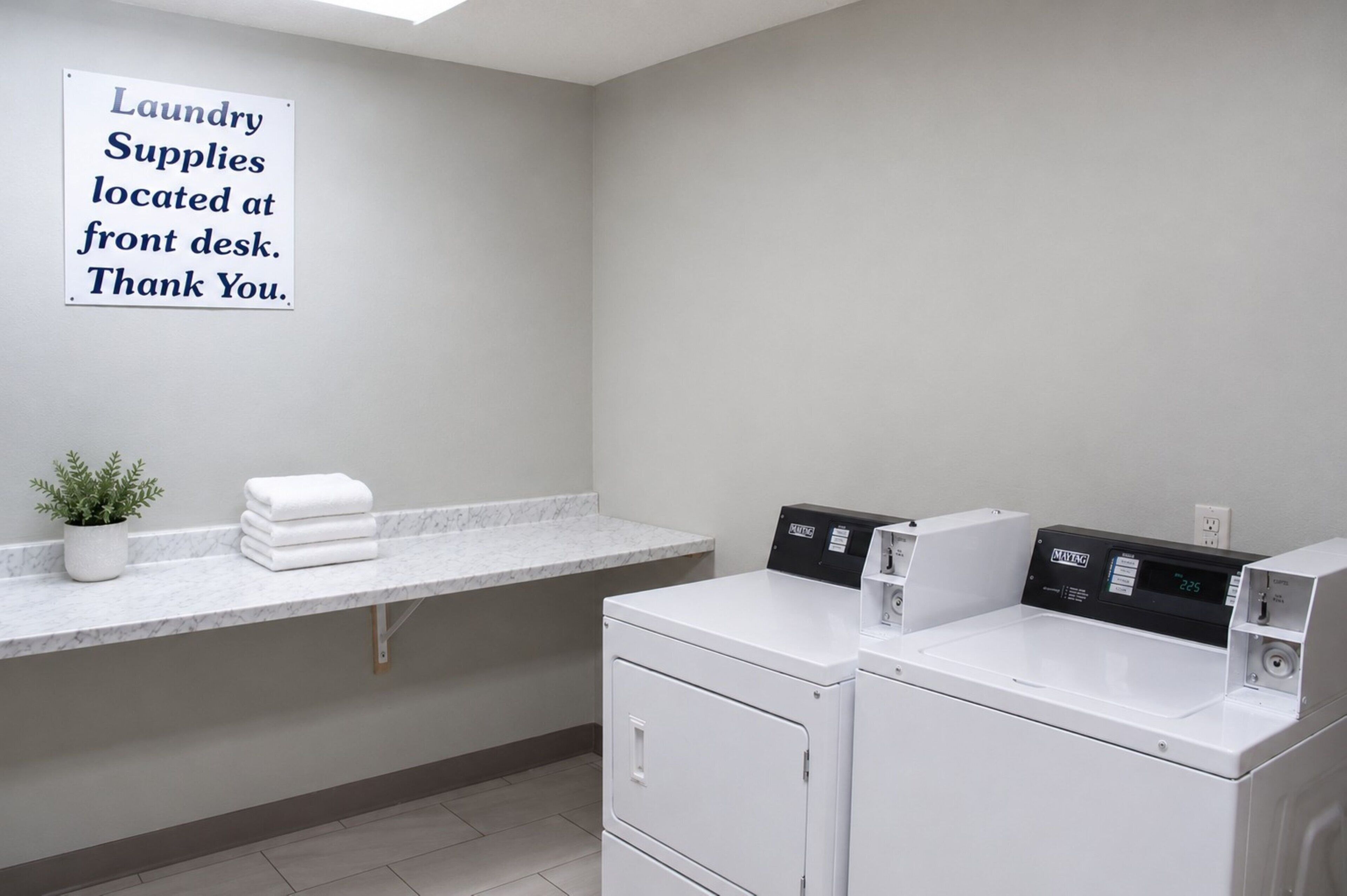 A laundry room with a sign indicating supplies at the front desk.