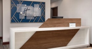 A reception desk with a modern design, featuring a geometric wall art piece above it and a sign indicating 'Holiday Inn Express & Suites'. - Holiday Inn Express Hotel & Suites Truth or Consequences by IHG (Truth or Consequences)