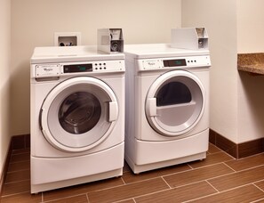 Two front-loading Whirlpool washers with digital displays, a control panel, and a coin return slot. - Holiday Inn Express and Suites Overland Park by IHG (Overland Park)