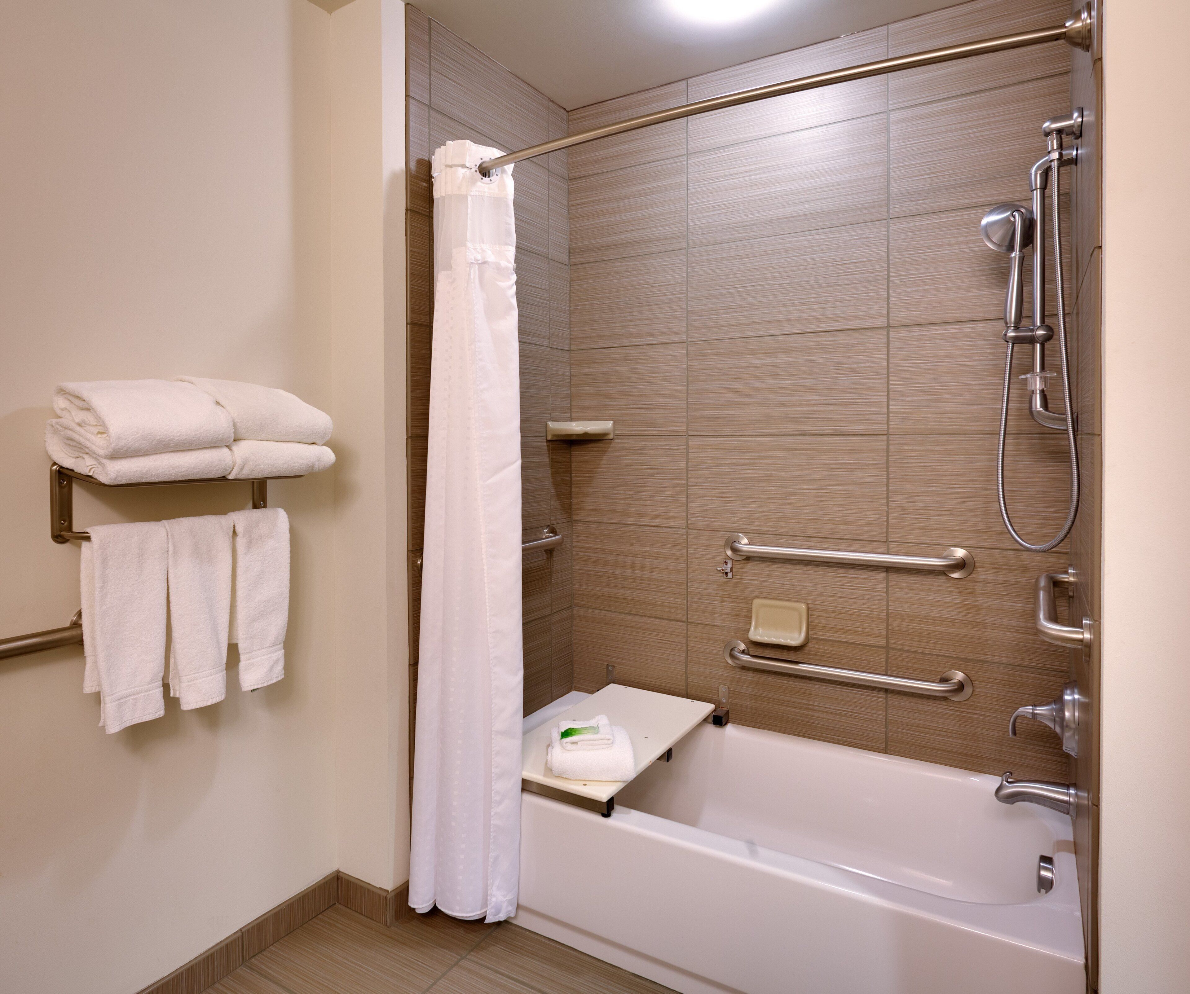 Un baño moderno con bañera, ducha y barras de apoyo.