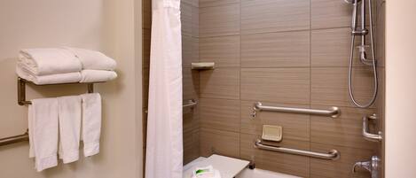 Un baño moderno con bañera, ducha y barras de apoyo.