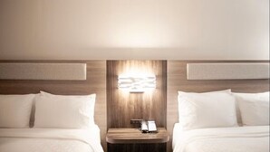 A hotel room with two beds, a nightstand with a phone, and a wall-mounted light fixture. - Holiday Inn Express and Suites Overland Park by IHG (Overland Park)