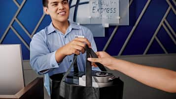 A person handing over a black bag to another individual at a counter with a sign reading 'Holiday Inn Express & Suites'.