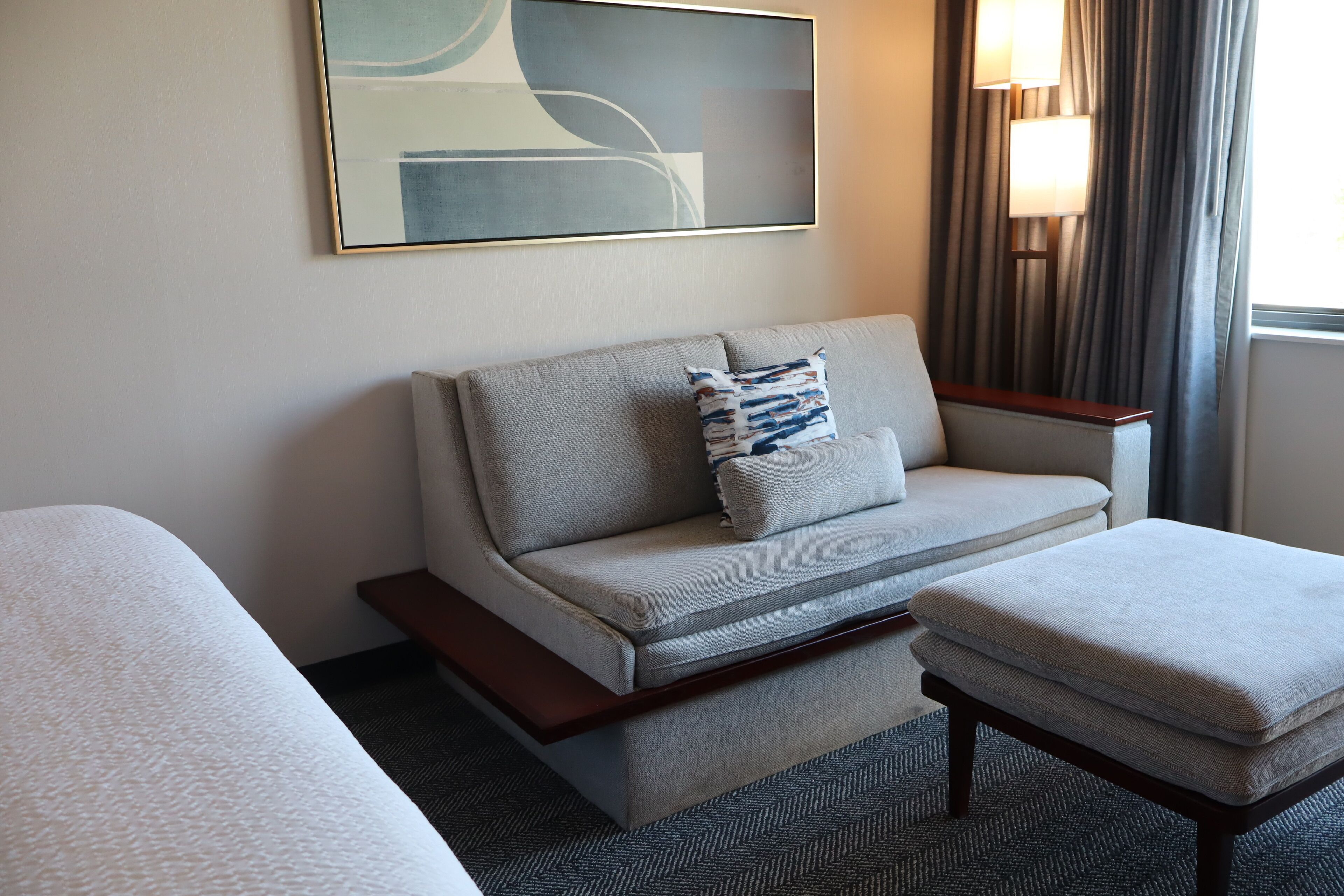 A hotel room with a sofa, a small table, and a bed.
