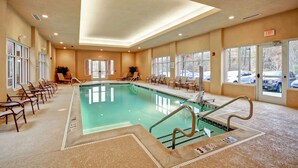 An indoor swimming pool with a clear view of the pool area, a set of stairs leading into the pool, and a seating area with chairs and tables. - Homewood Suites by Hilton Doylestown (Warrington)
