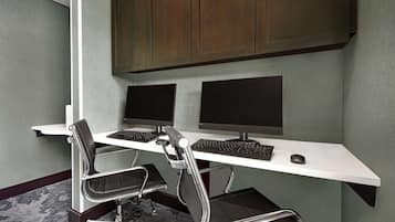 Un espacio de oficina moderno con un escritorio blanco, dos monitores, un teclado y dos sillas de oficina.