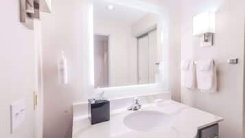 A modern bathroom with a large mirror, white sink, and towel rack.