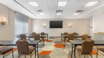 A conference room with a large table, chairs, a projector screen, and a carpet with geometric patterns.