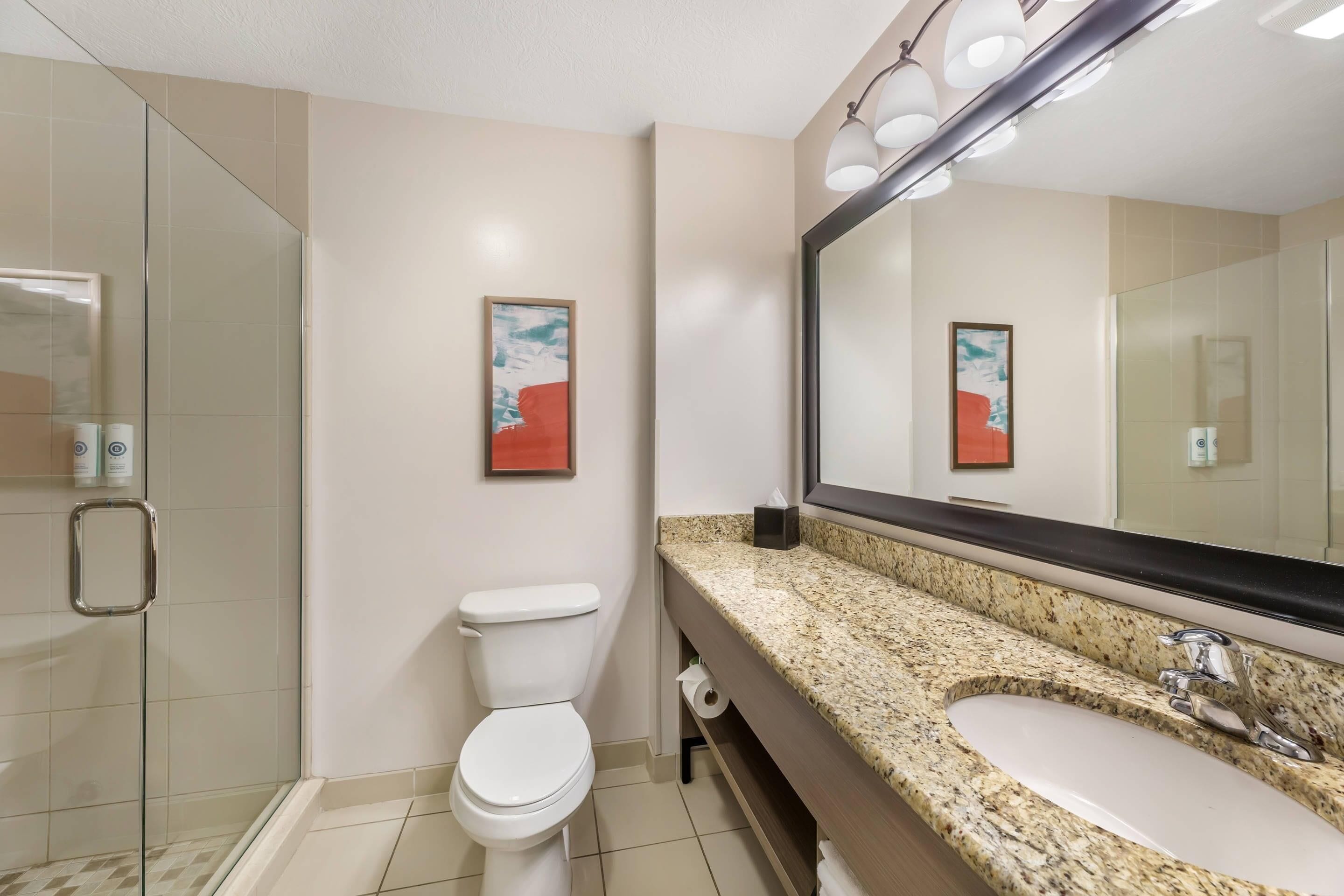 A bathroom with a toilet, sink, and glass shower enclosure.