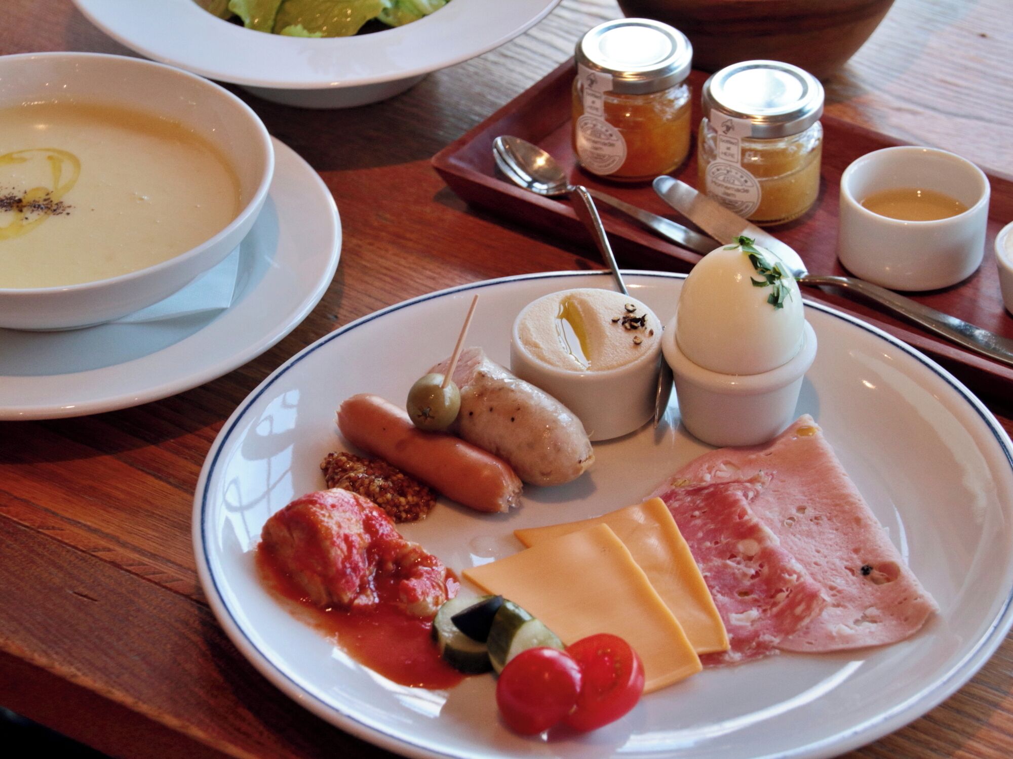 Un plato con diversos alimentos, como queso, jamón, tomates y aceitunas.