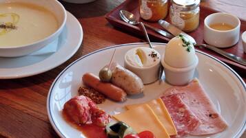 Un plato con diversos alimentos, como queso, jamón, tomates y aceitunas.