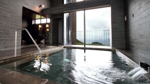 Ein moderner, überdachter Pool mit Blick auf das Meer durch große Fenster.