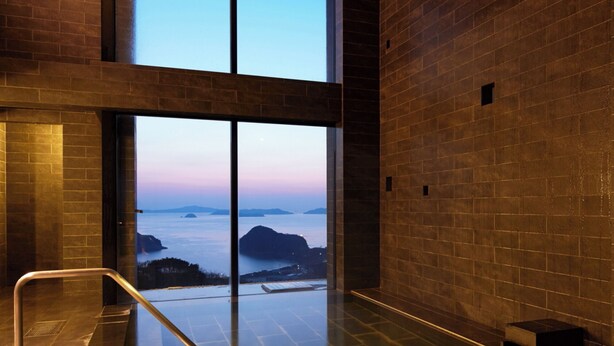 Ein moderner Wellnessraum mit einer großen Glasdoor zu einem Blick auf das Meer.