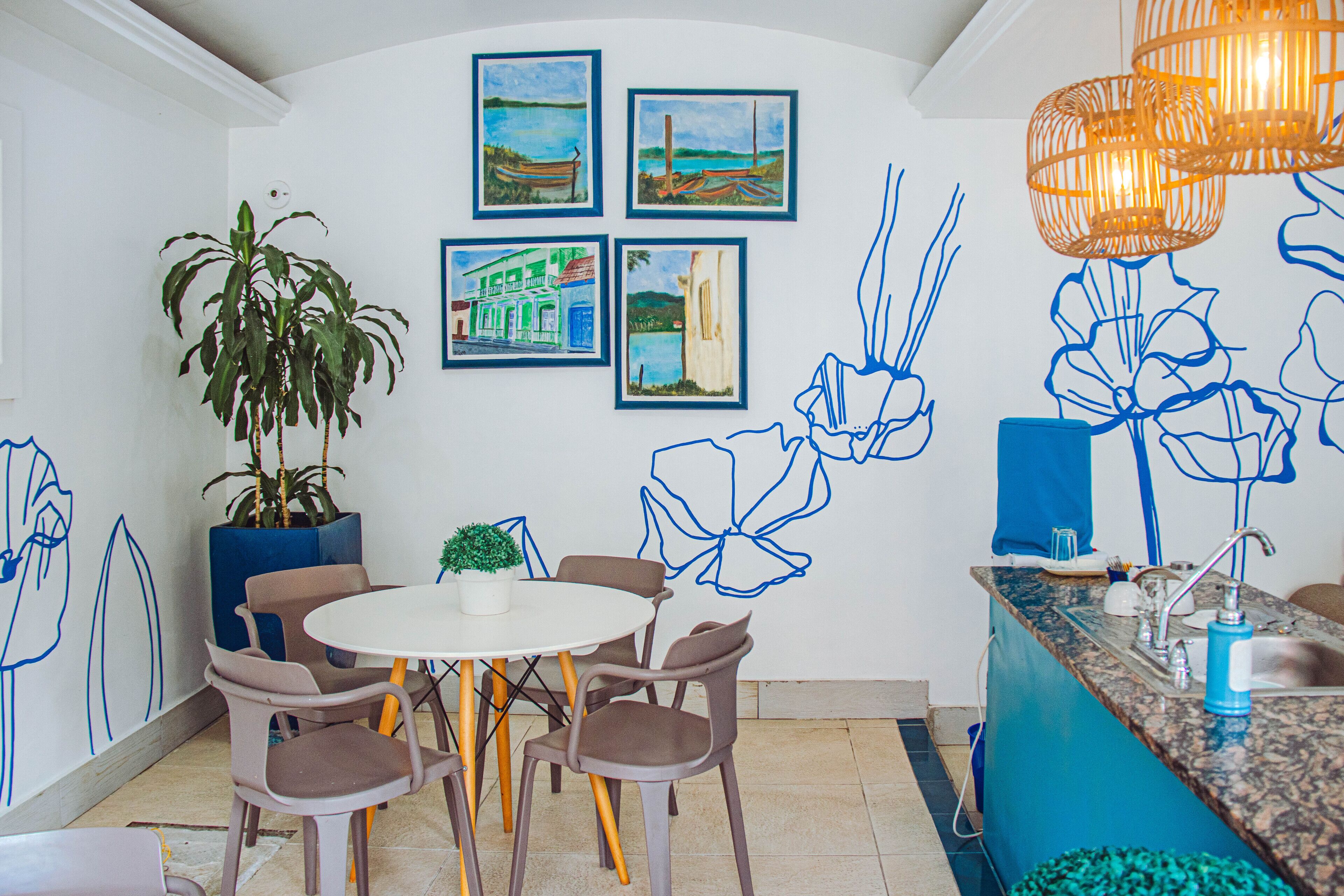 A dining area with a round table and chairs, a potted plant, and wall art.