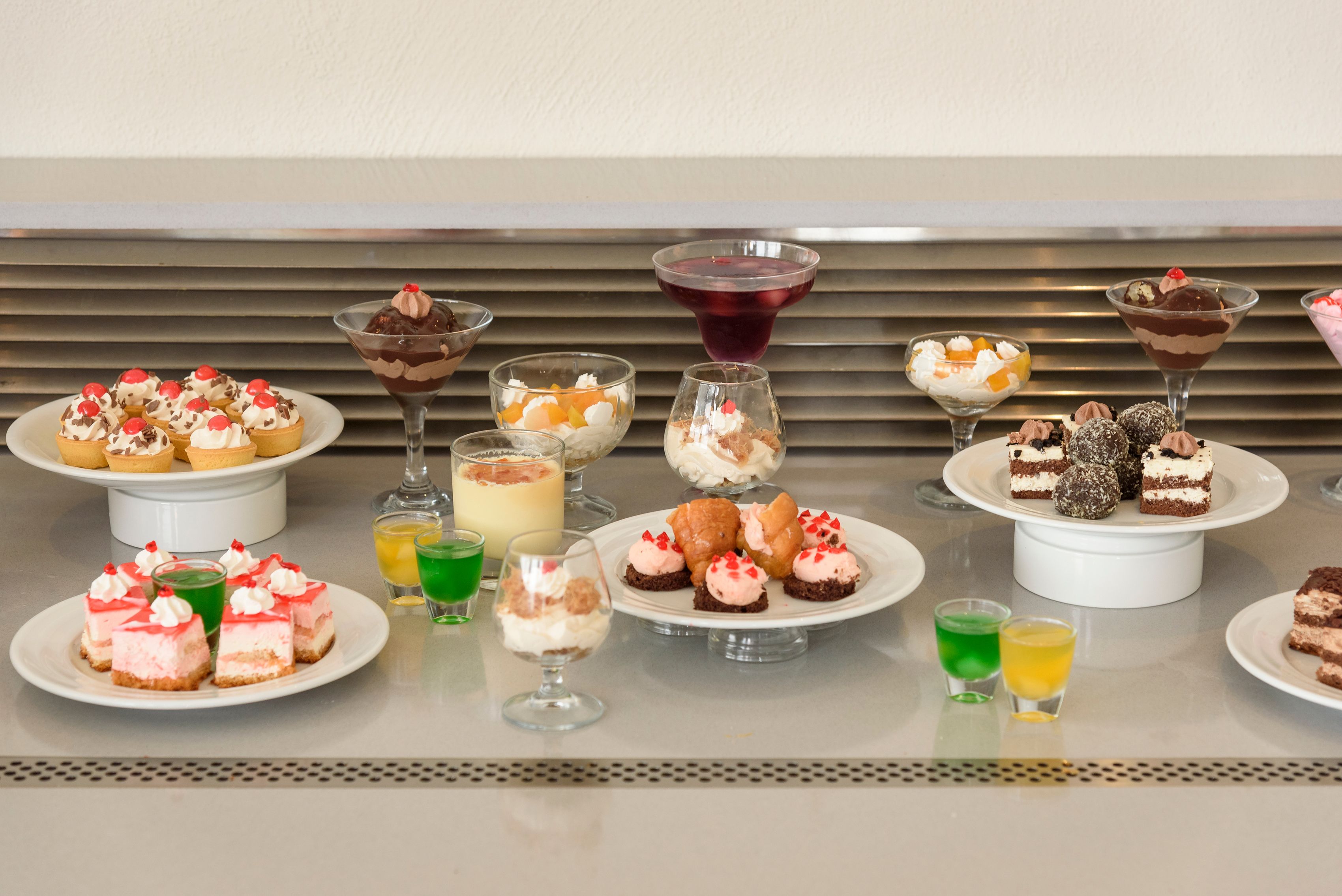 Diversas sobremesas e bebidas dispostas em um buffet.