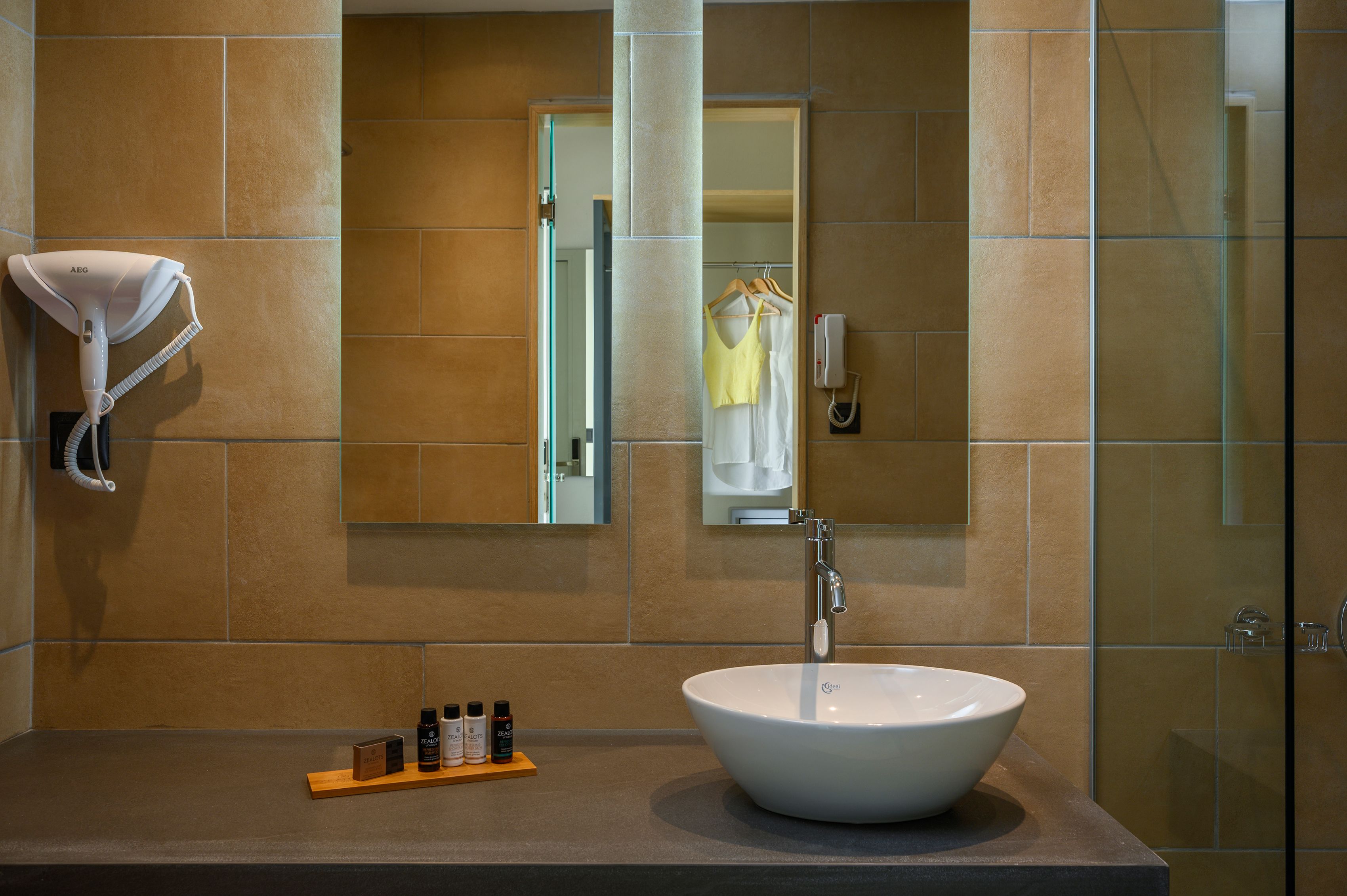 A bathroom with a large sink, a towel rack, a mirror, and a glass shower enclosure.