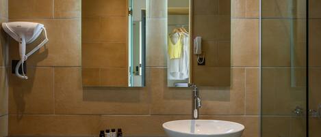 A bathroom with a large sink, a towel rack, a mirror, and a glass shower enclosure.